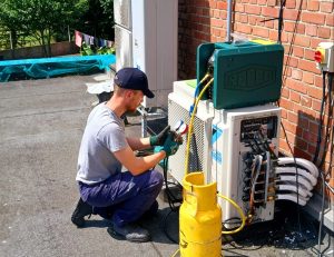 Un technicien de Pouchain effectuant la maintenance d'un système de climatisation sur un toit.